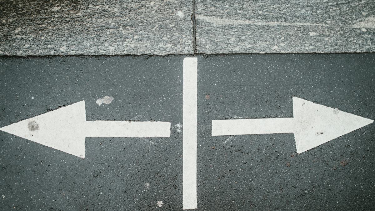 Two white arrows pointing in opposite directions on asphalt