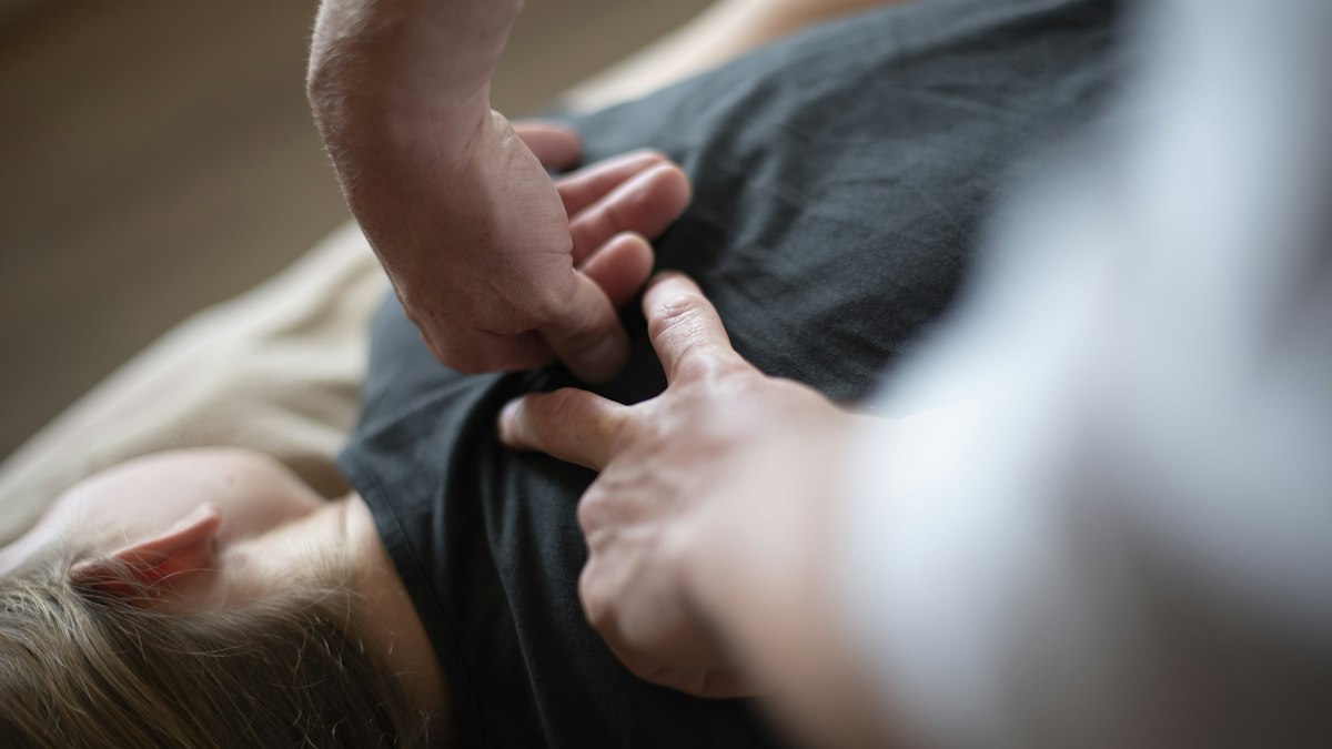 Hands pressing on a person's upper back during a treatment