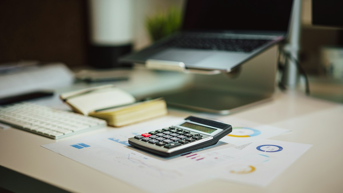 A calculator sitting on top of a table next to a laptop