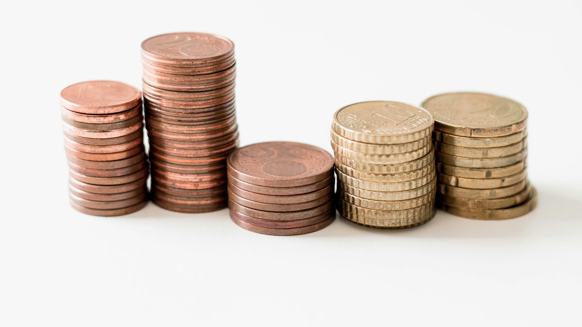 Stacked round gold-colored coins on white surface